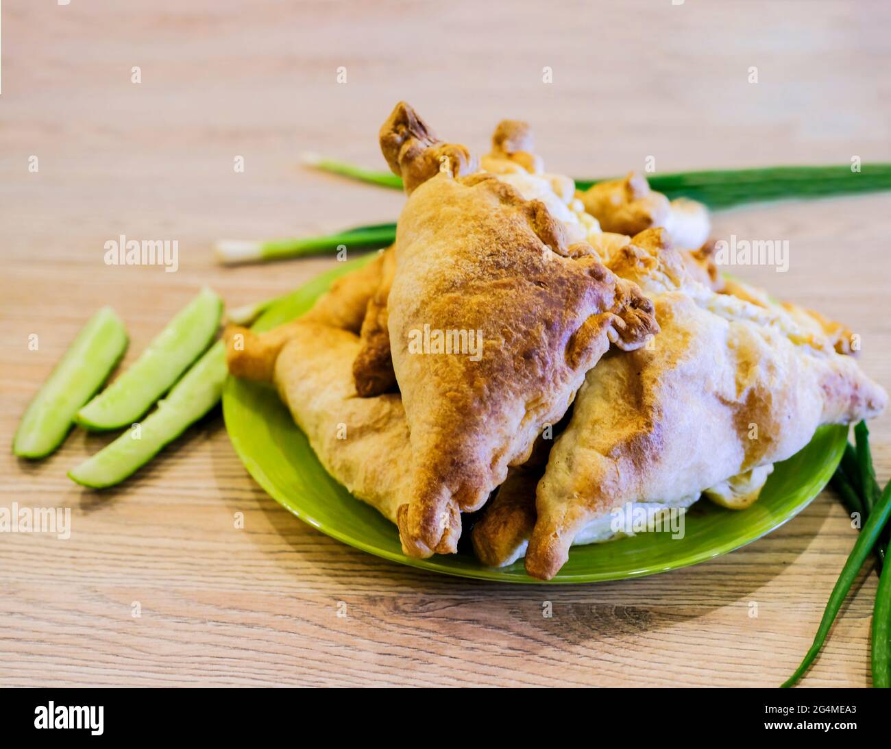 Si tratta di una vera e propria samsa uzbeka su un piatto con verdure e cipolle verdi. Cucina nazionale Foto Stock
