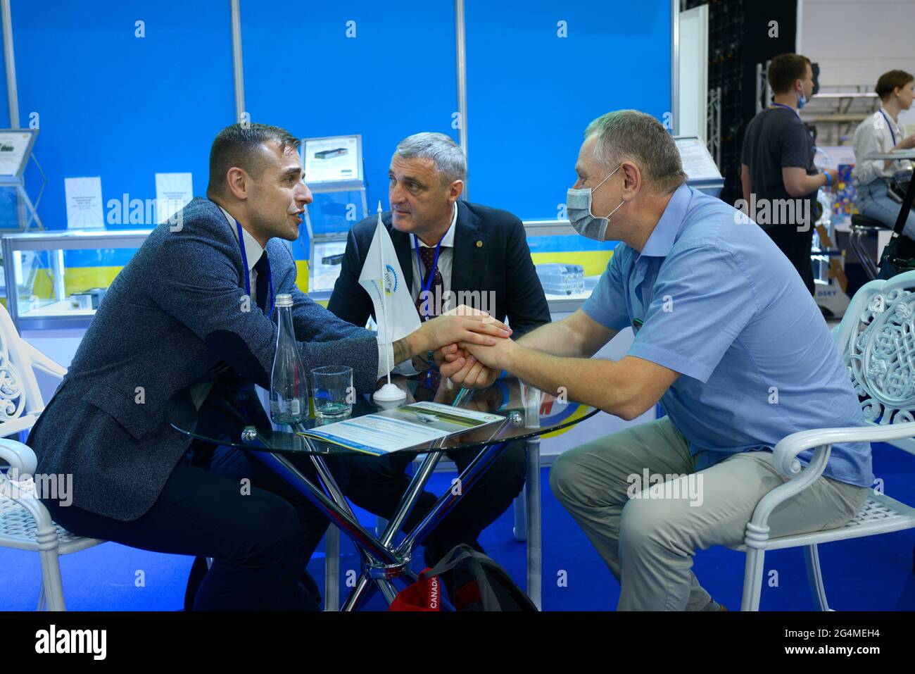 Buon affare. Due uomini d'affari che scuotono le mani seduti al tavolo nella zona lounge dopo le trattative . Mostra armi e sicurezza. 15 giugno 2021. Kiev, Foto Stock