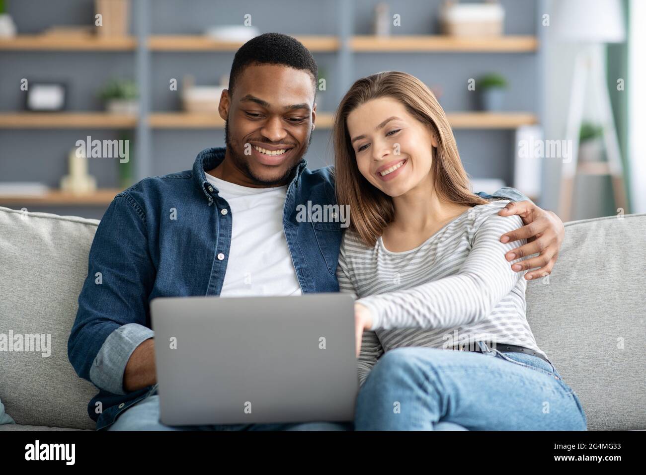 Felice giovane coppia interracial con il laptop a casa Shopping Online Foto Stock
