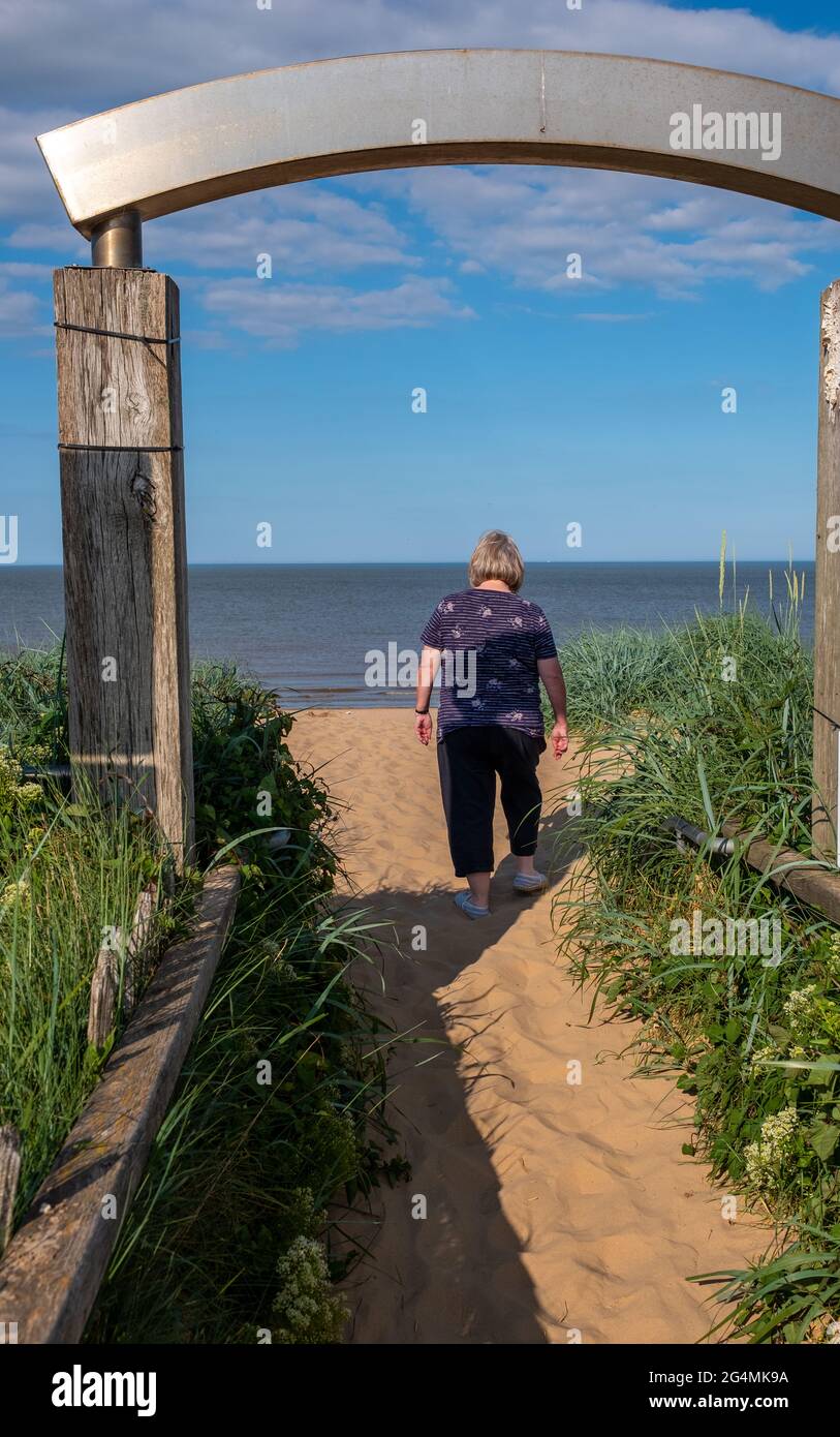 Una donna bionda ama camminare sulla spiaggia sabbiosa in una calda giornata estiva a Mablethorpe, Lincolnshire Foto Stock