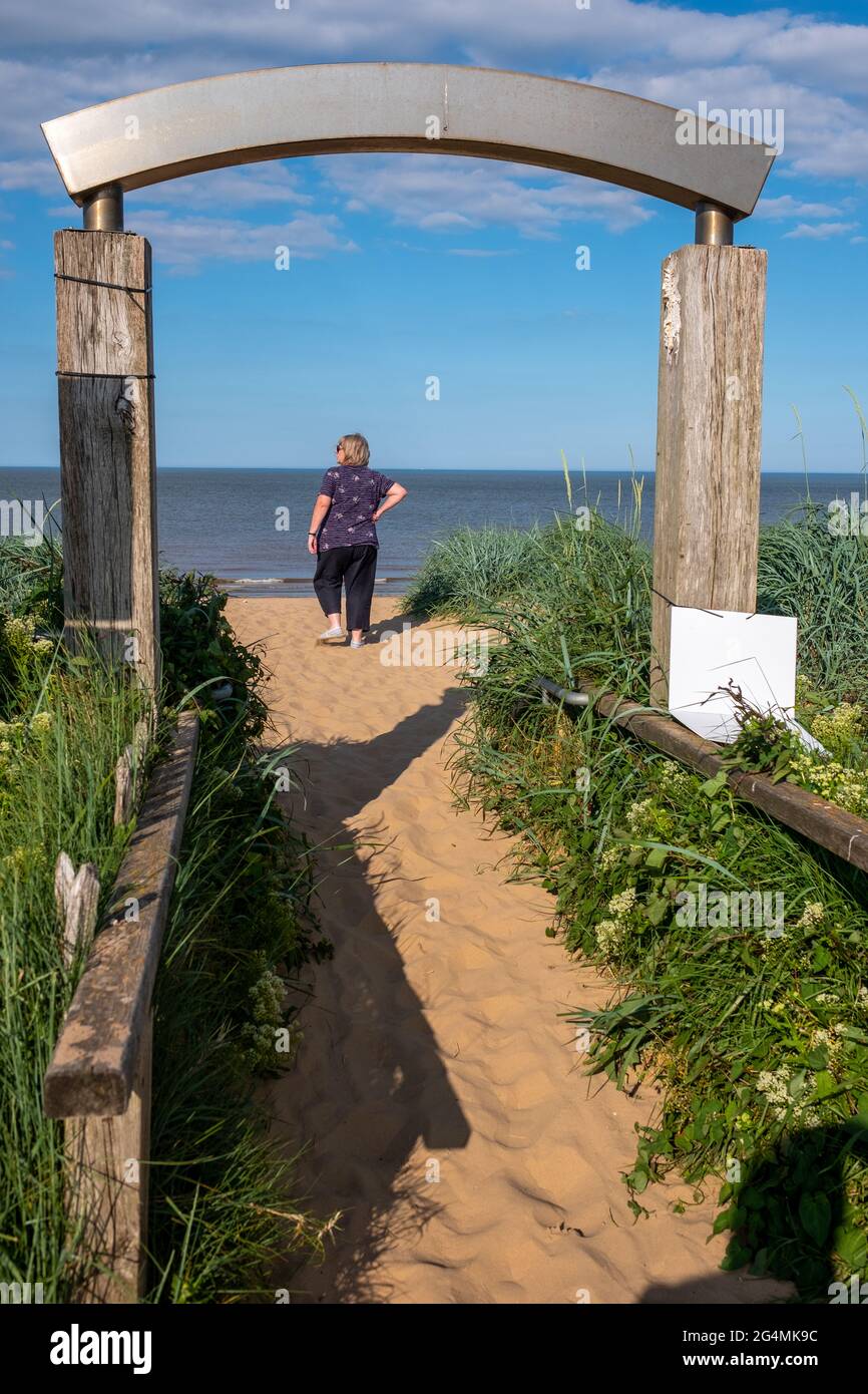 Una donna bionda ama camminare sulla spiaggia sabbiosa in una calda giornata estiva a Mablethorpe, Lincolnshire Foto Stock