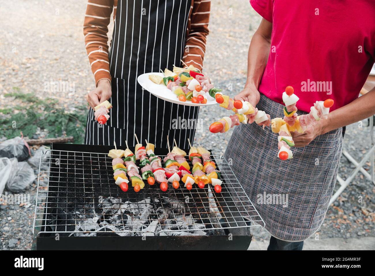 Una coppia grigliando maiale e barbecue in cena festa. Concetto di cibo, persone e tempo di famiglia. Foto Stock
