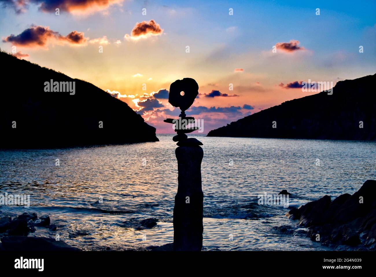 Pietre equilibranti sulla spiaggia di Port Quin al tramonto. Foto Stock