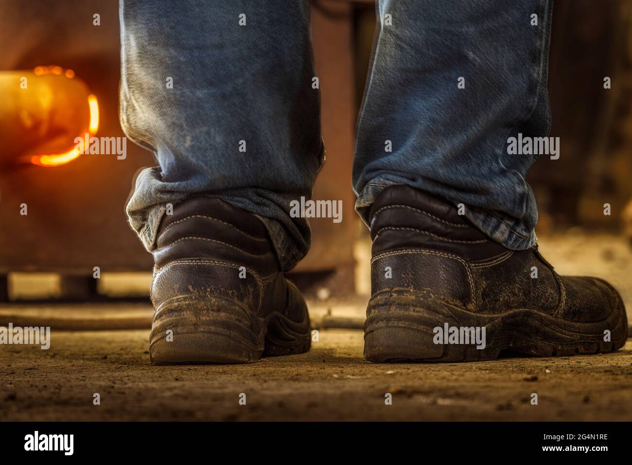 Concetto di lavoro. Primo piano di jeans da uomo e stivali da lavoro con un  forno caldo sullo sfondo Foto stock - Alamy