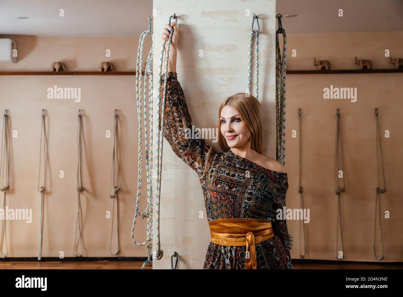 Donna matura in studio di yoga in piedi e reggendo corde appendenti yoga. Concetto di yoga Iyengar Foto Stock
