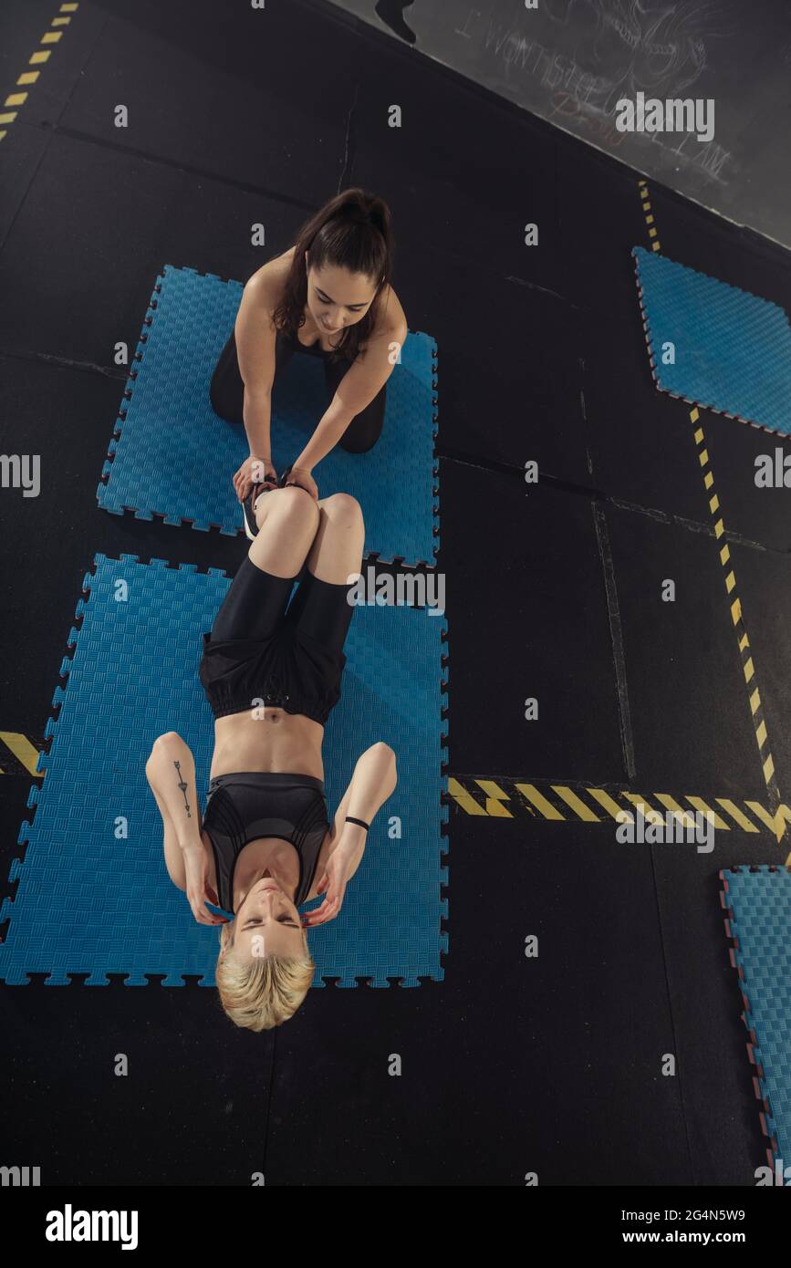 Donne in bianco e nero abbigliamento sportivo su un vero gruppo corpo combattimento allenamento in palestra treno per combattere, kickboxing con un allenatore. Foto Stock