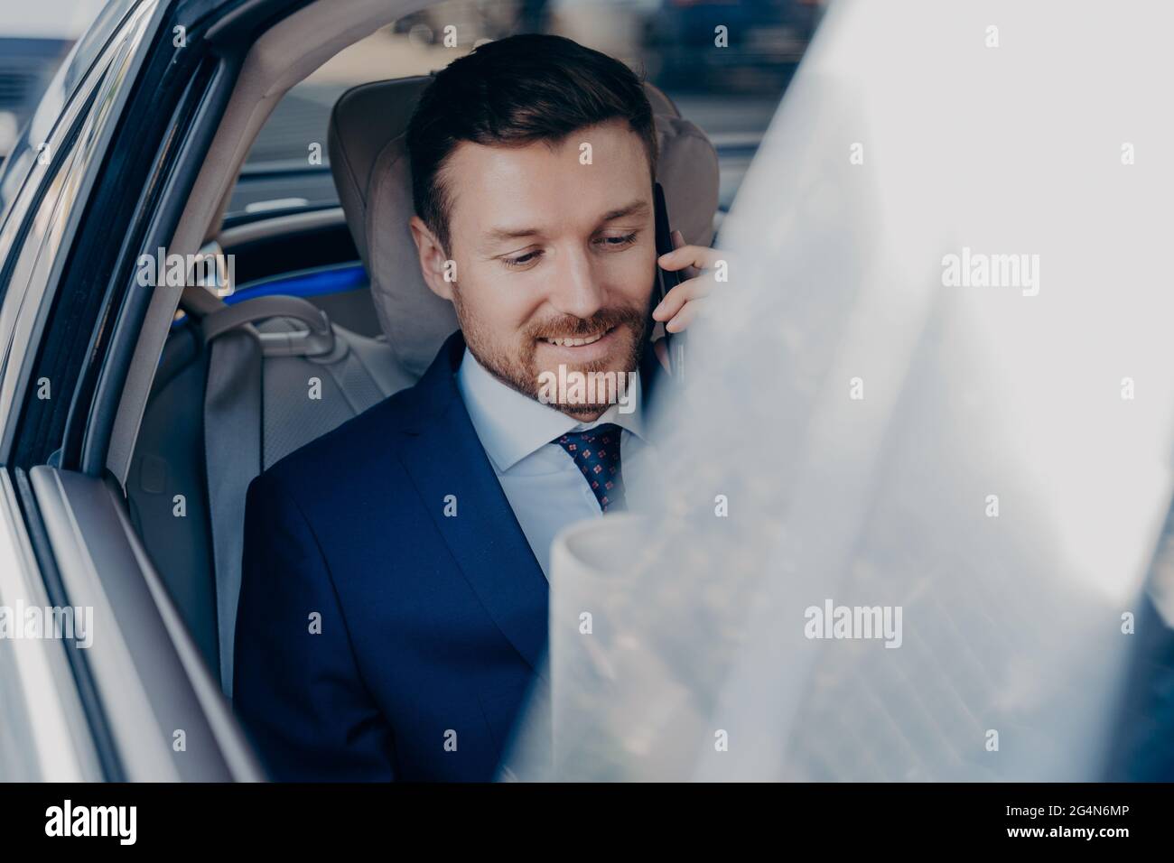 L'uomo d'affari corre in auto nera sul sedile del passeggero e parla sul cellulare Foto Stock
