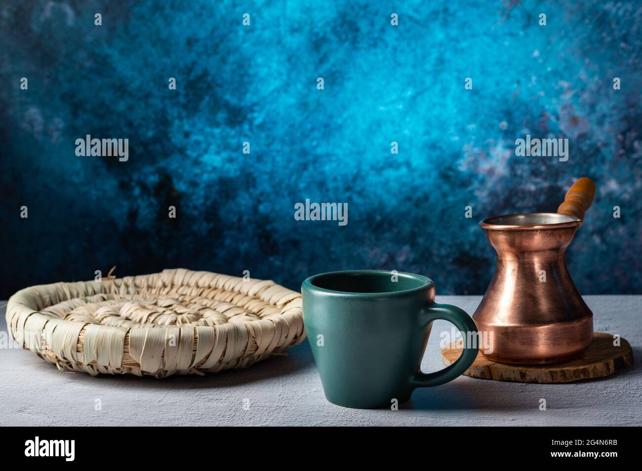 Tazza di ceramica verde e tazza di caffè di rame. Un piatto di paglia per dolci. Caffetteria. Vista frontale. Foto Stock