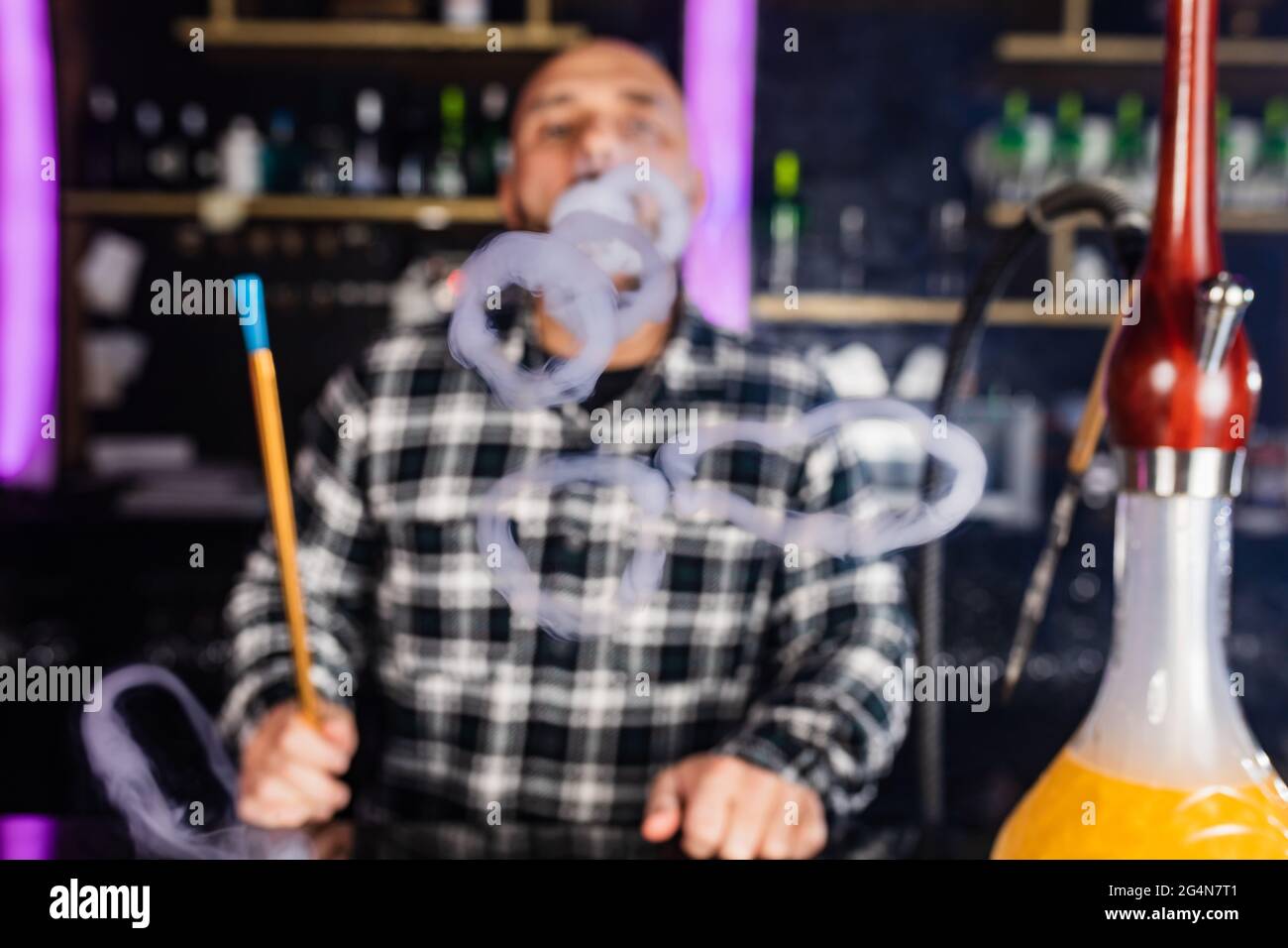 uomo che fuma hookah tradizionale in un night club Foto Stock