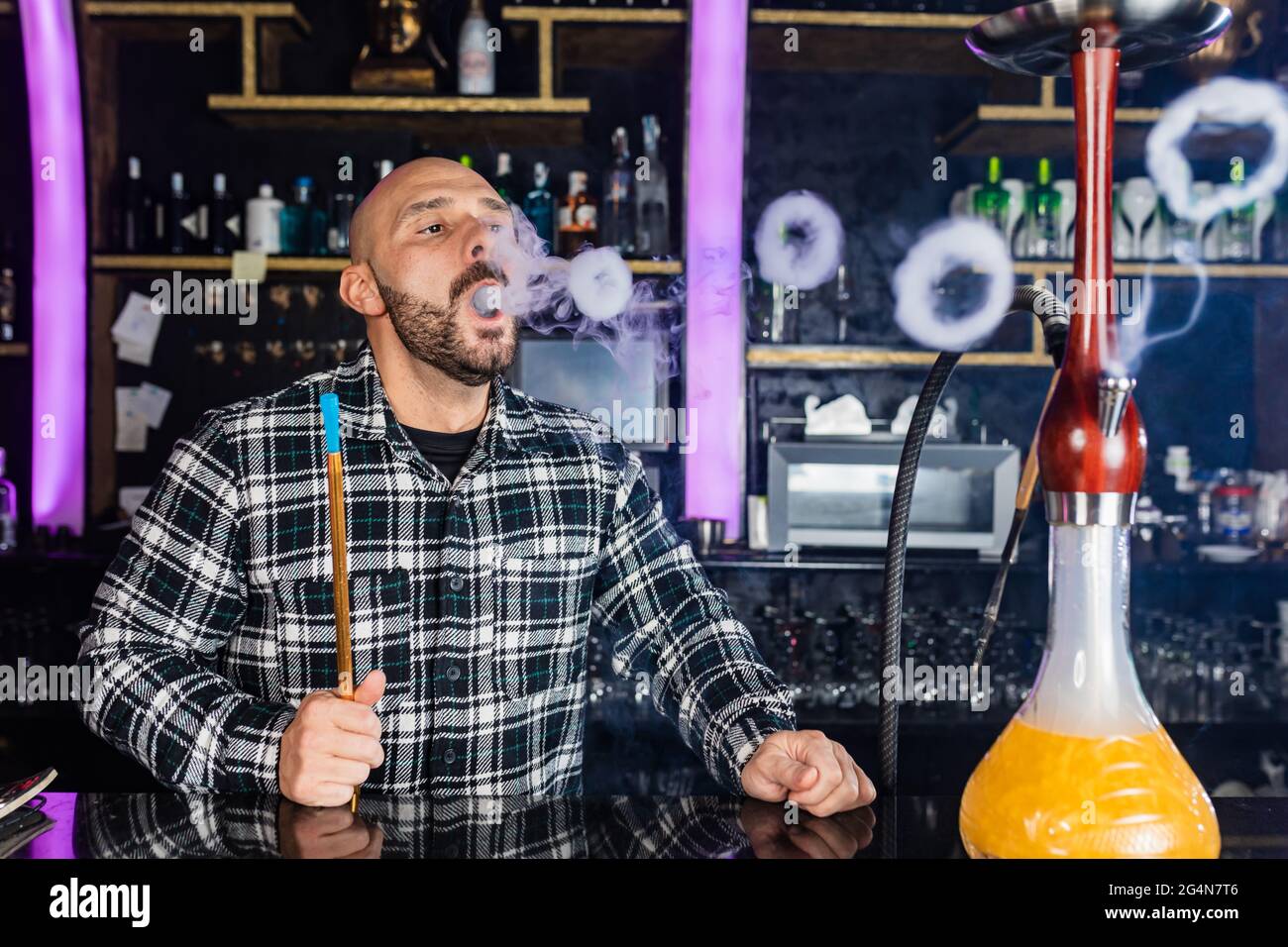 uomo che fuma hookah tradizionale in un night club Foto Stock