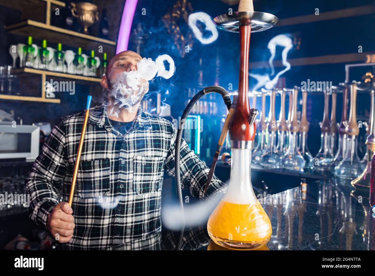 uomo che fuma hookah tradizionale in un night club Foto Stock