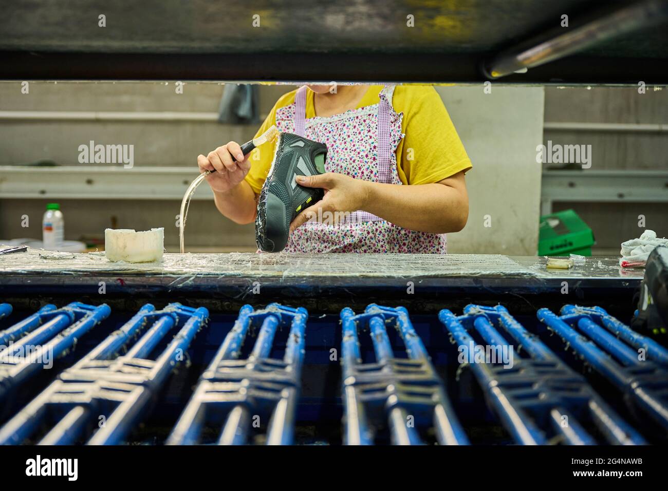 Particolare di lavoro che applica colla alla suola delle scarpe in una  linea di produzione di calzature cinesi Foto stock - Alamy