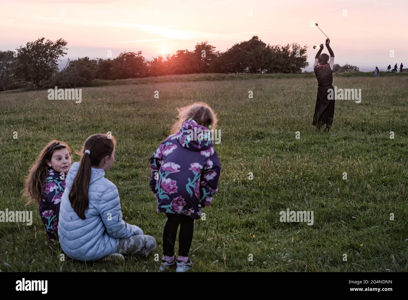 Contea di Meath, Irlanda. 21 Giugno 2021. Tre bambini piccoli guardano un giocoliere che si esibisce al tramonto. Centinaia di persone si sono riunite nella collina di Tara ieri sera per il Solstizio d'Estate del 2021. Ogni anno, la gente si riunisce sulla collina di Tara per celebrare il solstizio estivo, che è stato un luogo spirituale e storico per migliaia di anni. (Foto di Natalia Campos/SOPA Images/Sipa USA) Credit: Sipa USA/Alamy Live News Foto Stock