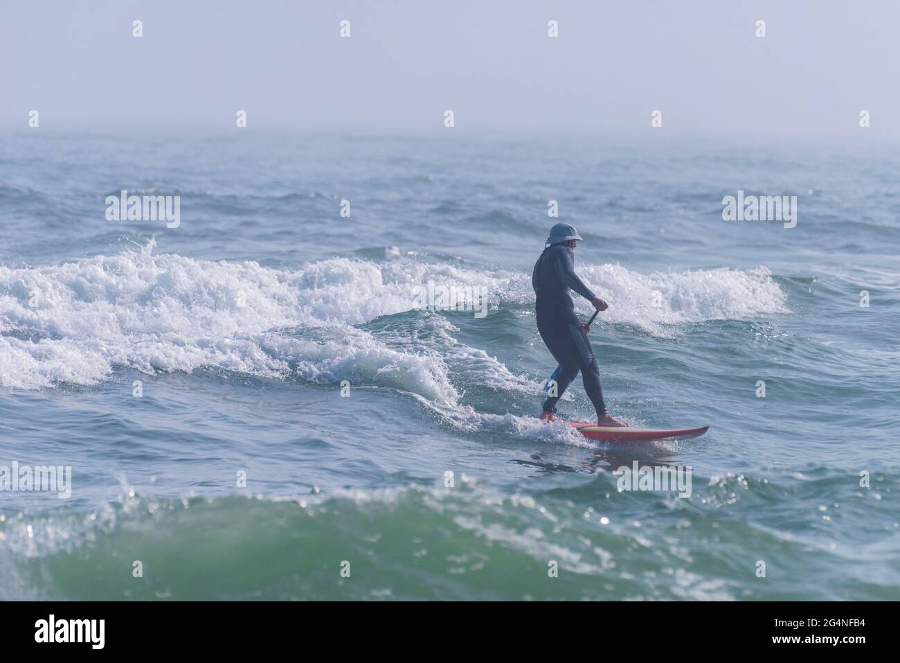 Un uomo surfs vicino alla spiaggia al Johnson Beach National Seashore in Florida il 26 marzo 2021. Foto Stock