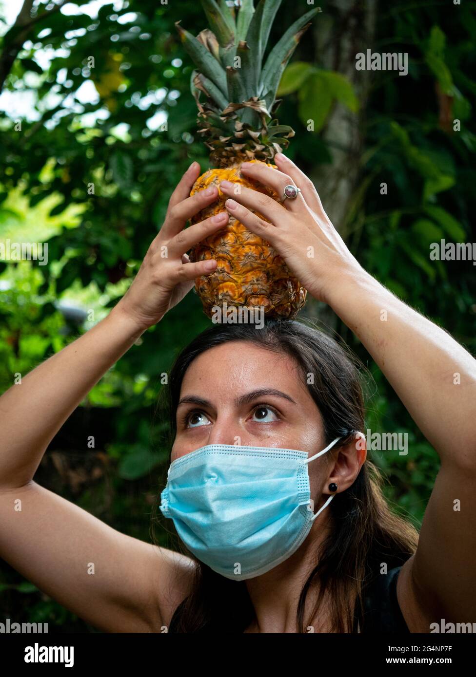 Ritratto di una donna latina in piedi teso con un ananas sulla sua testa Foto Stock