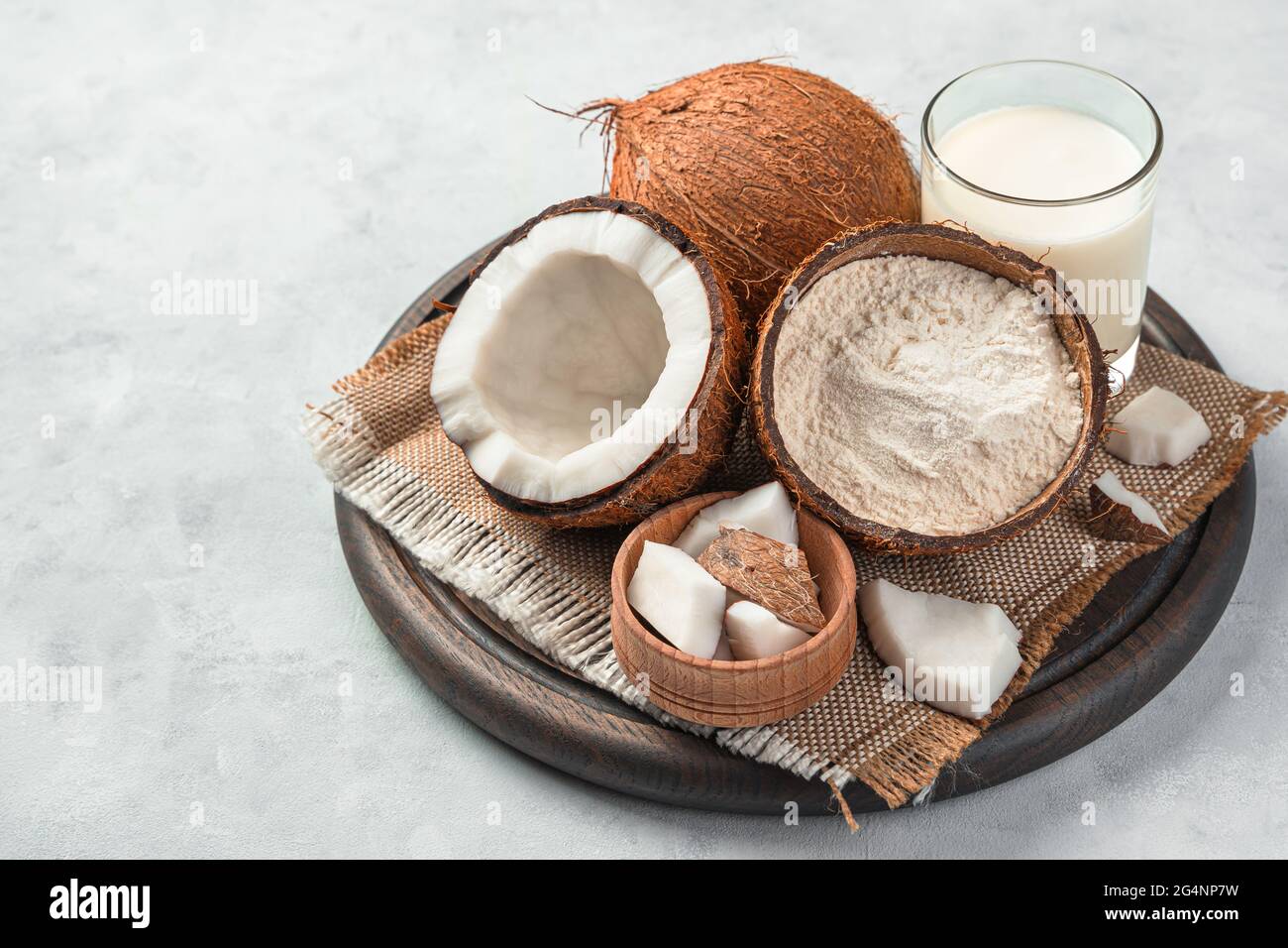 Cocco fresco e prodotti di cocco su sfondo grigio. Farina di cocco e latte di cocco. Foto Stock