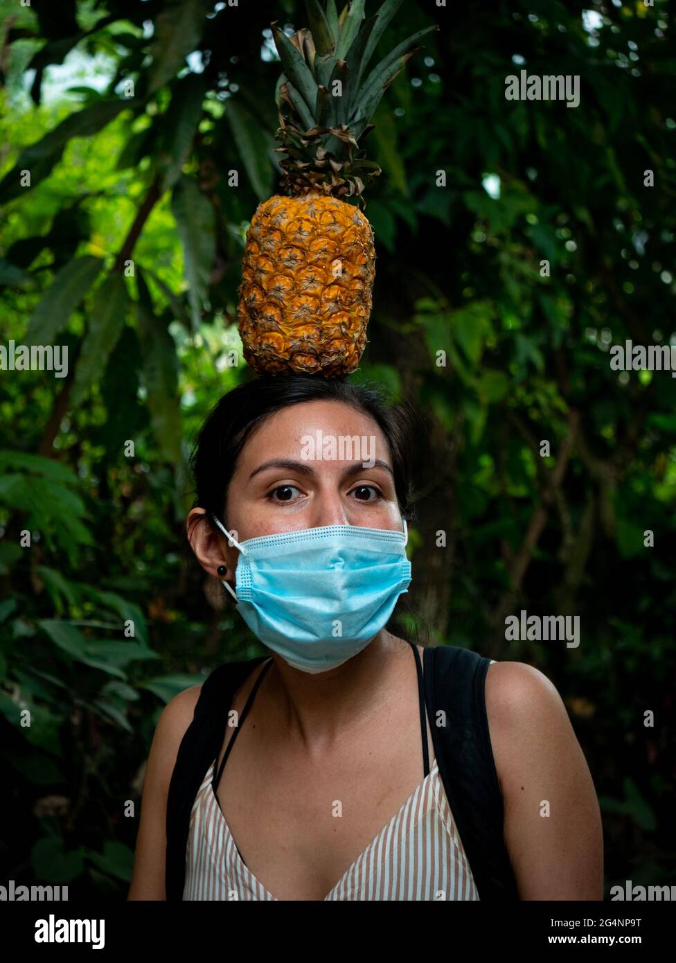 Donna Latina in piedi teso con un ananas in cima alla sua testa Foto Stock