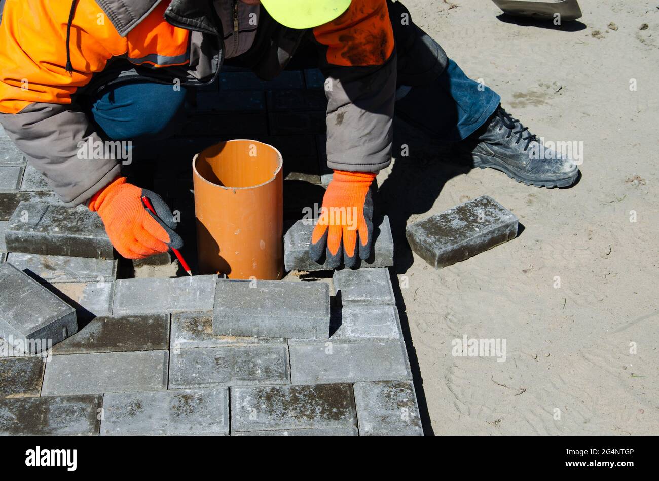 Costruzione di pavimentazione vicino alla casa. Muratore posiziona blocchi di pietra di pavimentazione di calcestruzzo per costruire su un Foto Stock