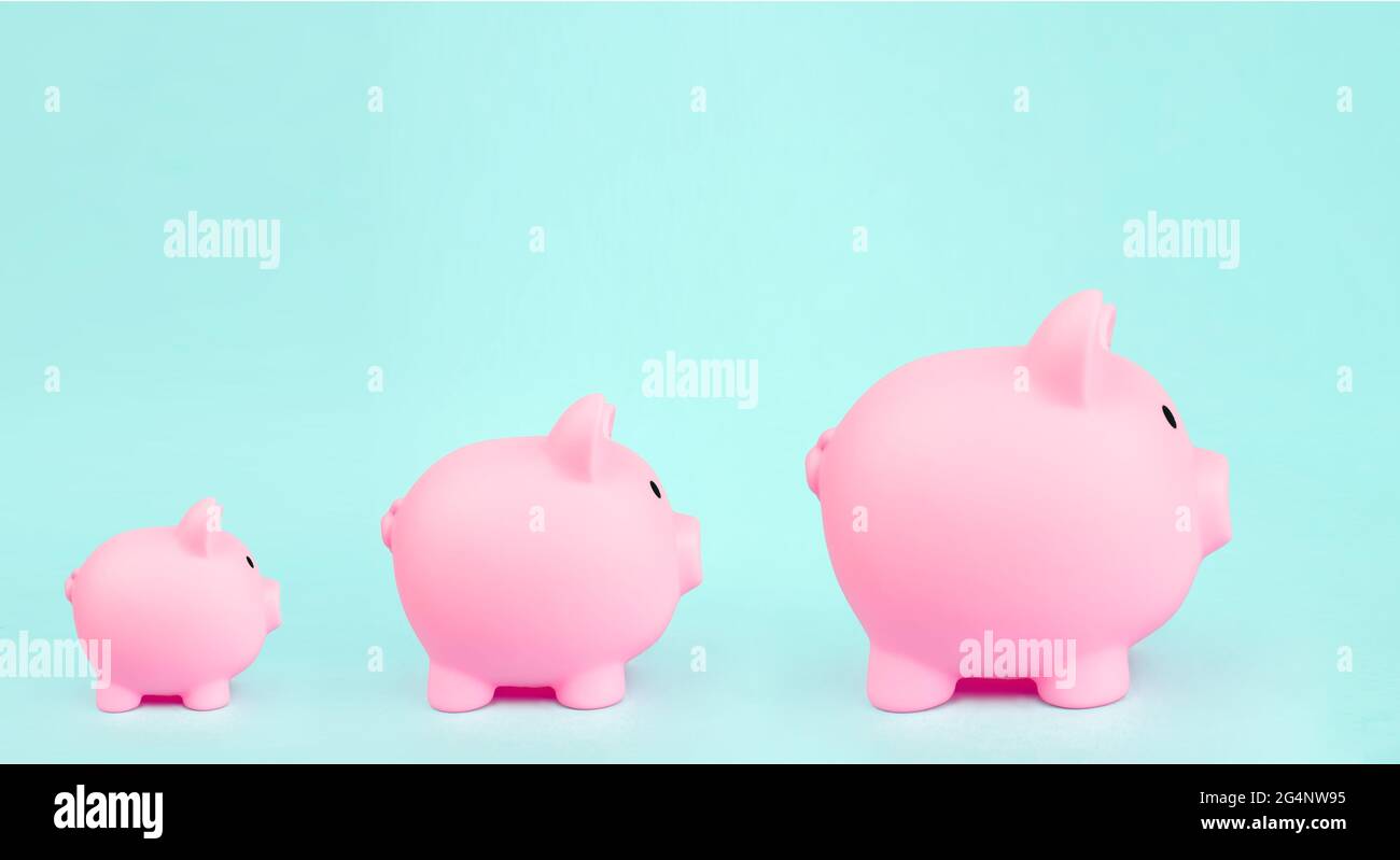 Tre pink piggy bank su sfondo blu. Concetto di crescita finanziaria Foto Stock