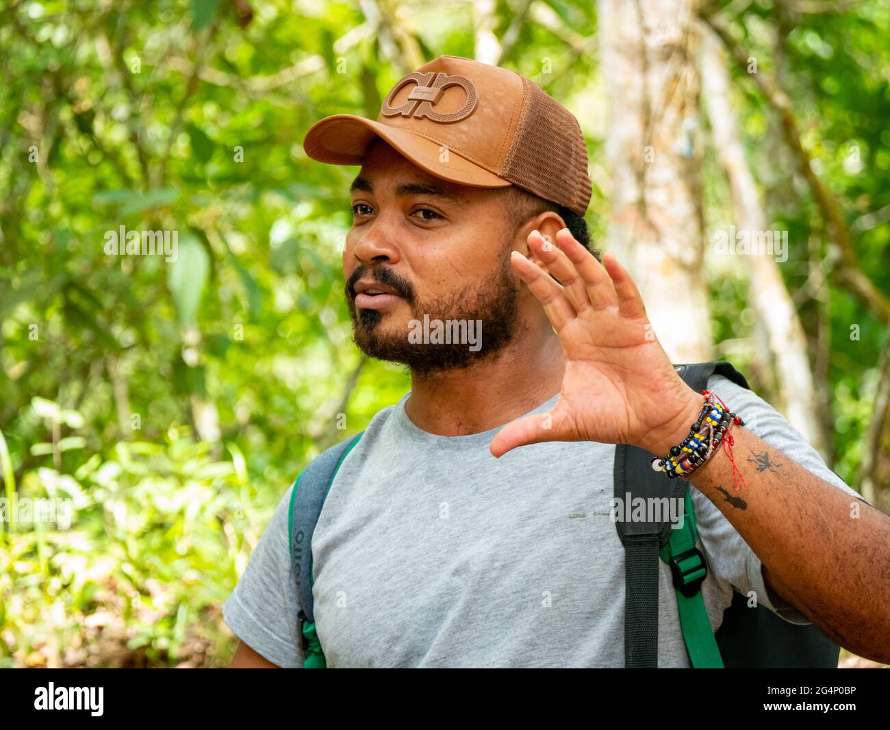 Minca, Magdalena, Colombia - 19 2021 maggio: L'uomo latino bruno con la sua pelle indossa un cappuccio e si trova nella foresta circondata da un lotto di natura Foto Stock