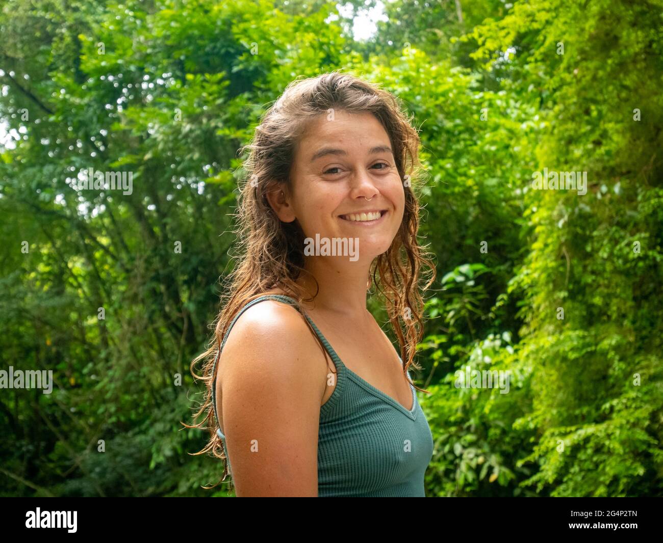 Minca, Magdalena, Colombia - 19 2021 maggio: Donna caucasica sorride alla macchina fotografica e splende dai raggi del sole vicino al fiume Foto Stock
