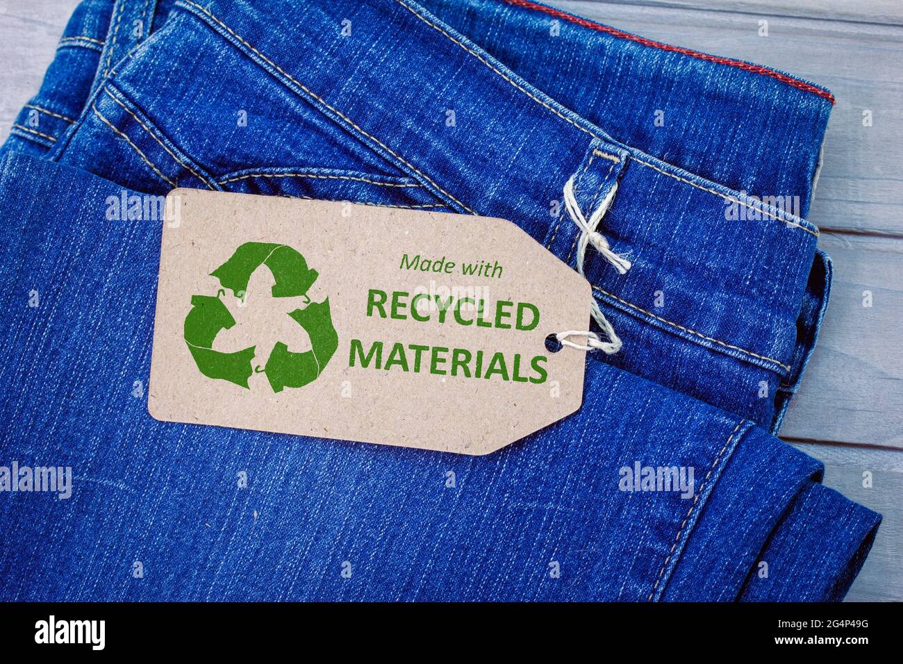 Realizzato con materiali riciclati etichetta su jeans con icona di abbigliamento ecologico. Moda sostenibile e concetto di shopping etico Foto Stock