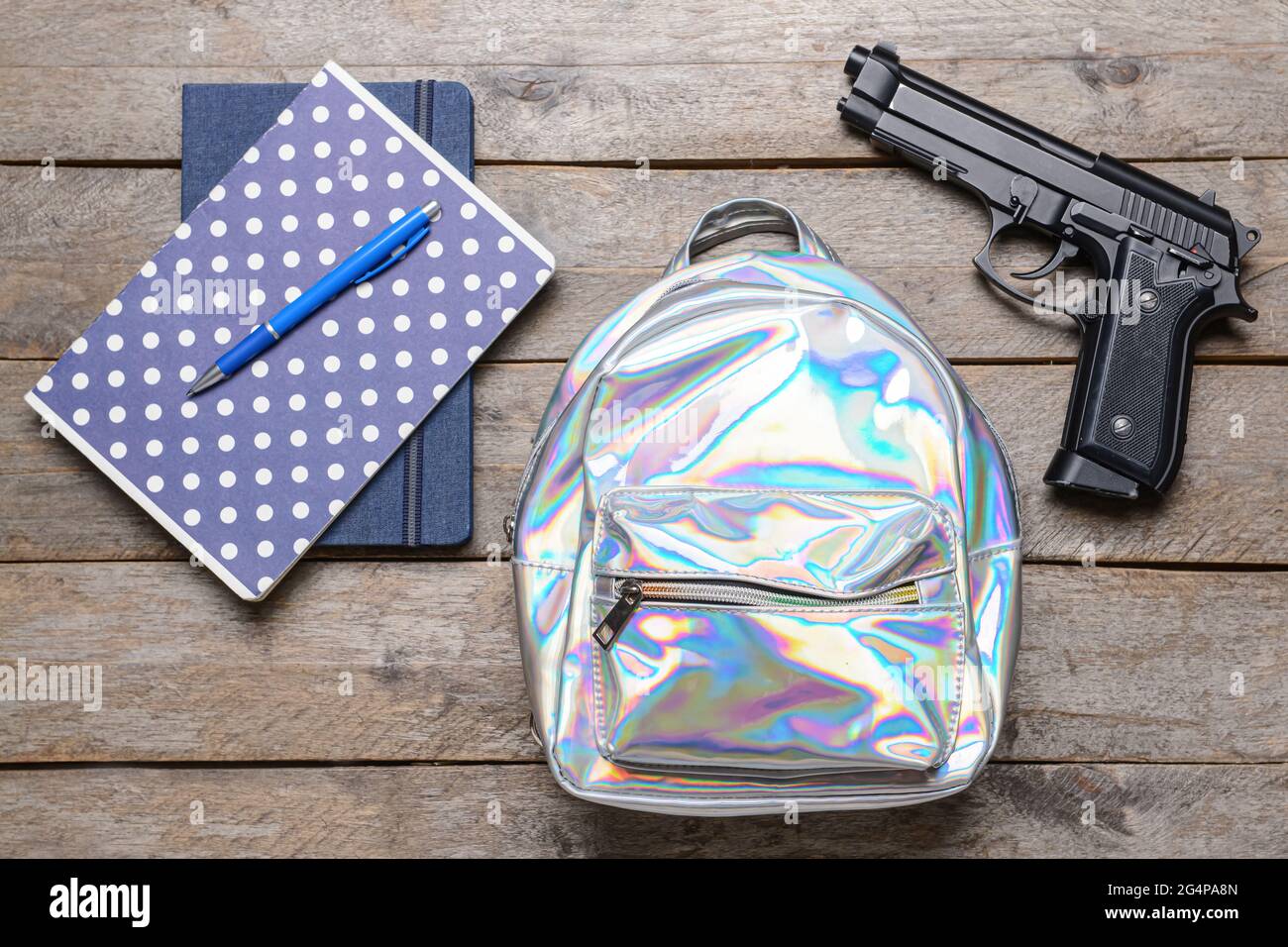 Pistola e zaino con cancelleria su sfondo di legno. Concetto di ripresa scolastica Foto Stock