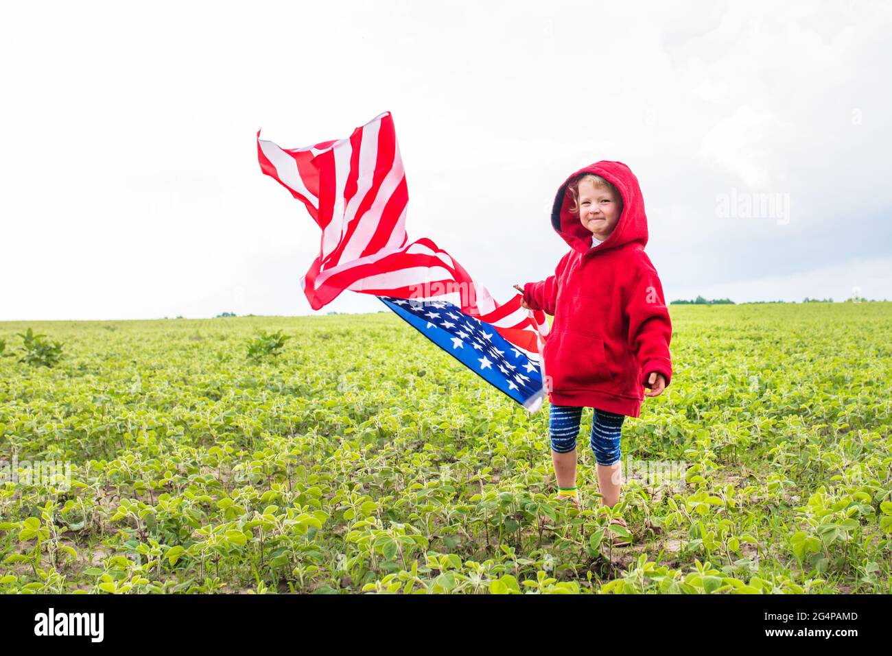 Adorabile bambina che tiene la bandiera americana all'aperto nella bella giornata estiva. USA festeggiano il 4 luglio . Concetto di giorno dell'indipendenza. Foto Stock