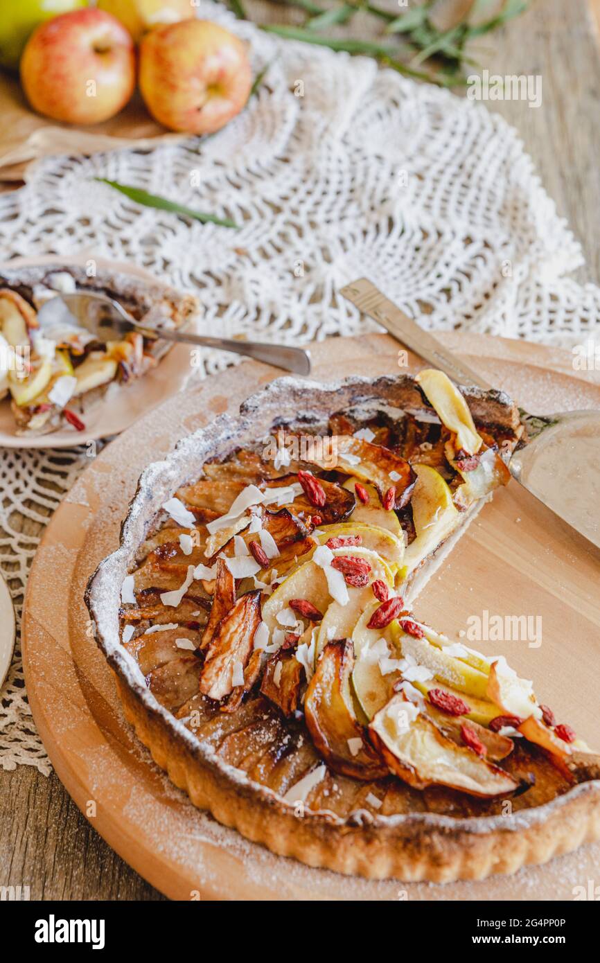 Torta di mele rustica, servita con gelato e frutti di bosco con fiori da tavola. Servito su un piatto di legno pigro Susan. Foto Stock