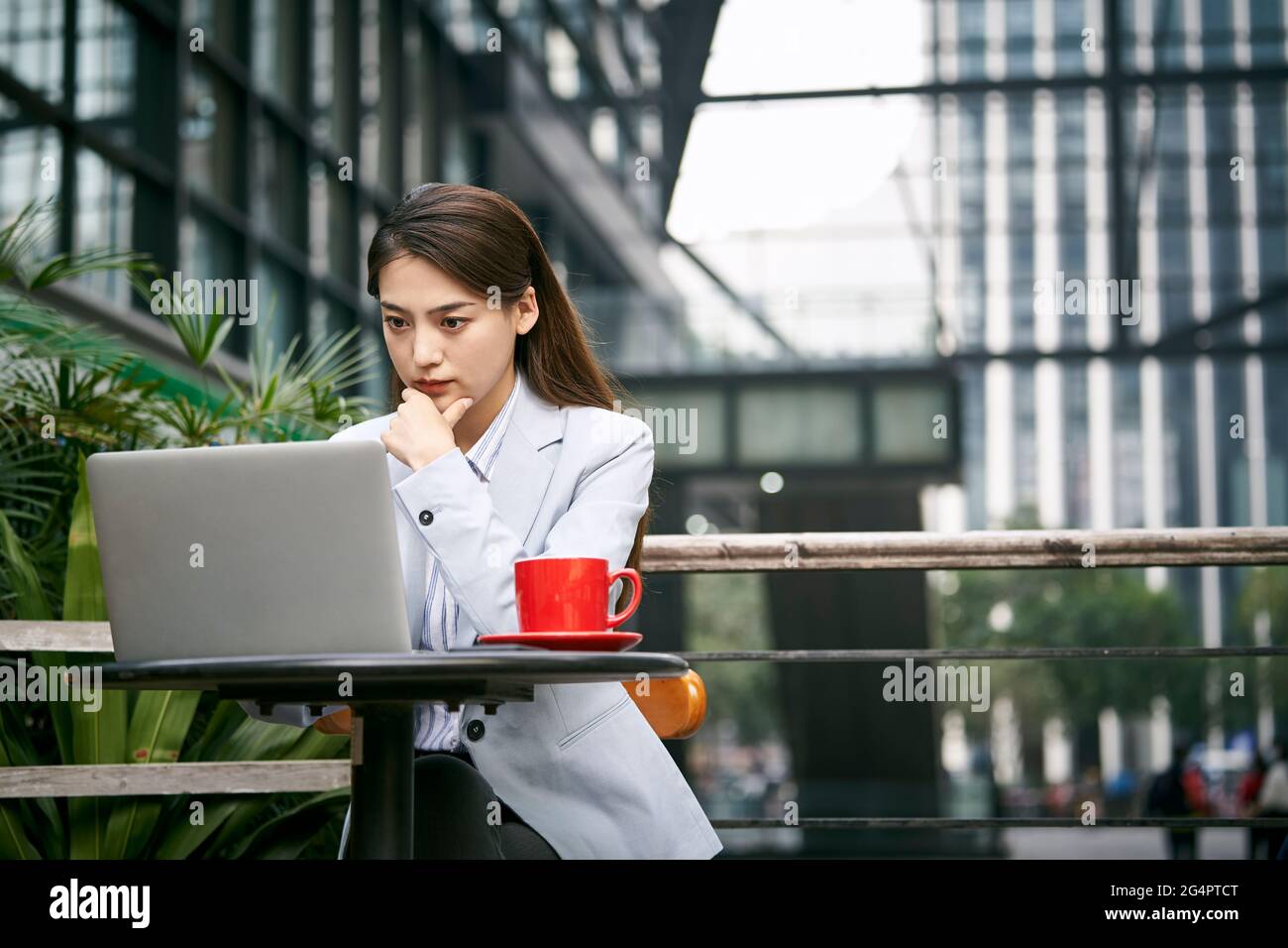 giovane donna d'affari asiatica che lavora all'aperto in una caffetteria utilizzando un computer portatile computer Foto Stock
