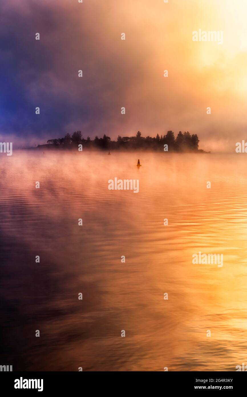 Variopinto e panoramico sorgere del sole in inverno freddo con nebbia e riflesso sul lago di Jindabyne in Australia. Foto Stock