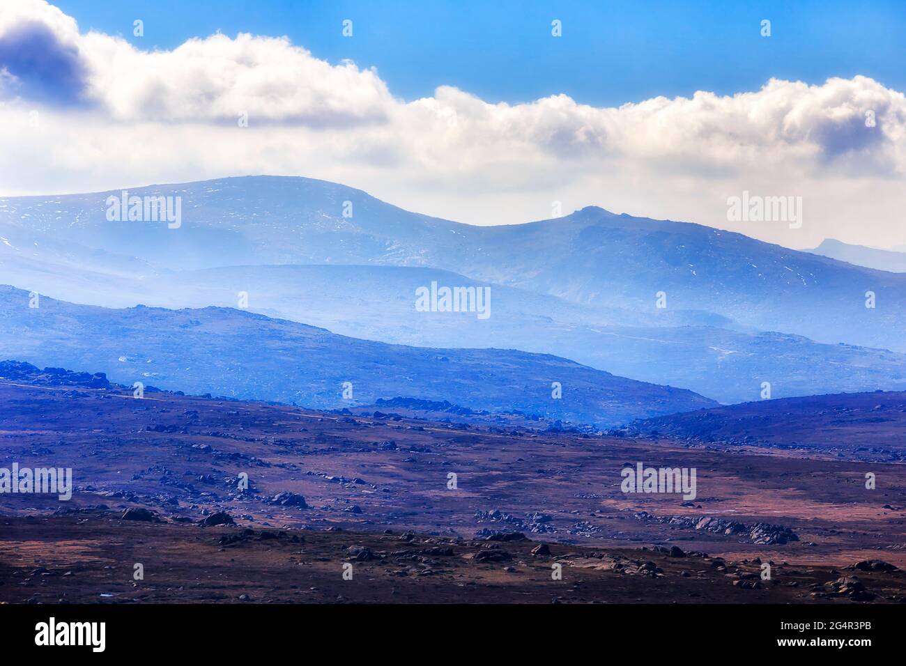 Strati di catene montuose e collinari alte nelle Snowy Mountains dell'Australia con la cima del monte Kosciuszko sotto le nuvole. Foto Stock