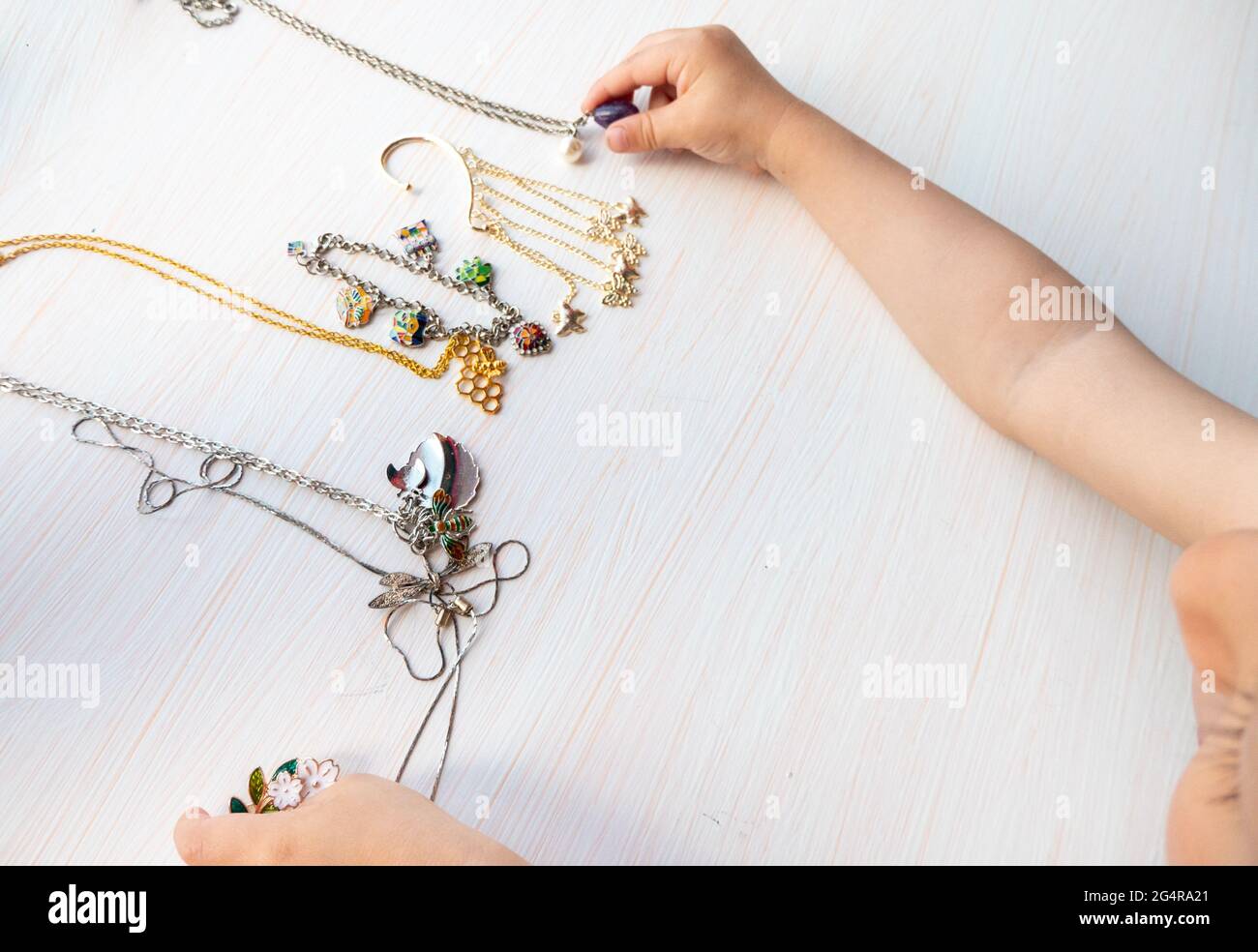 felicità delle donne - le mani dei bambini giocano con bijouterie estive chiare, su sfondo bianco Foto Stock