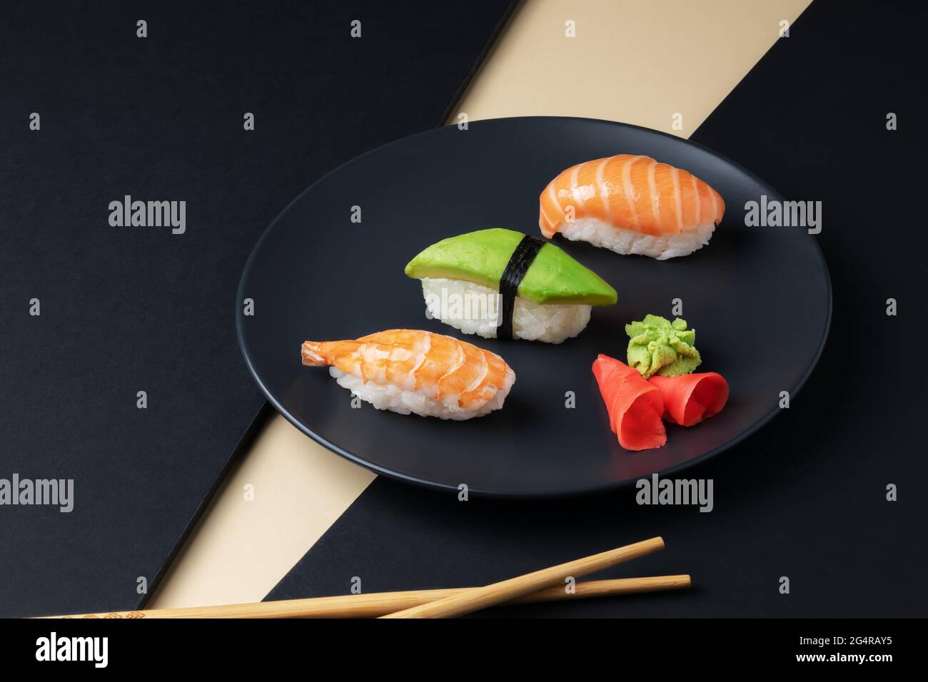 Cucina giapponese - Set di nigiri sushi con salmone, avocado e gamberi su un piatto nero con bastoncini. Foto Stock