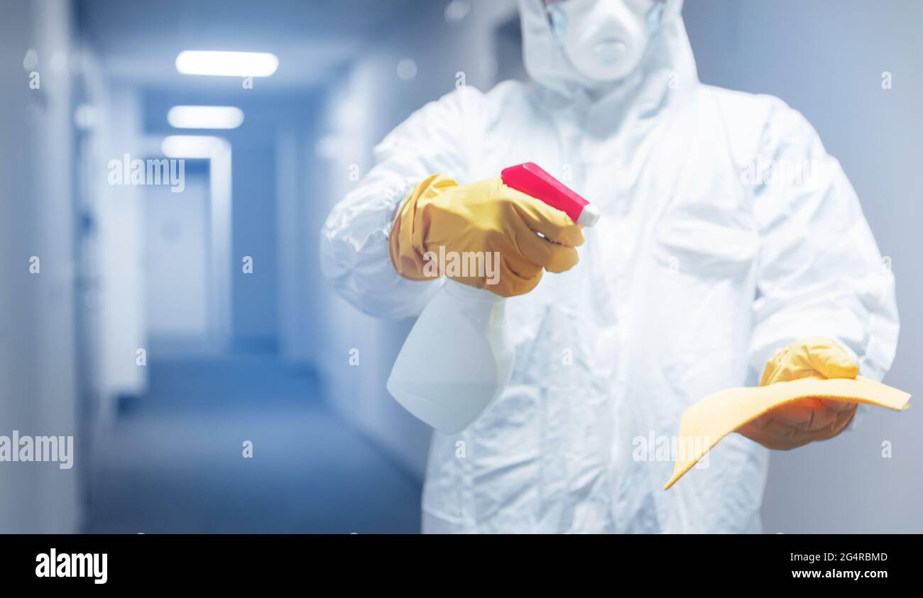 Disinfettare lavoratore in biorischio igienizzare e pulito casa appartamento vs infezione virus, uccidere i batteri. Tonalità blu. Foto Stock
