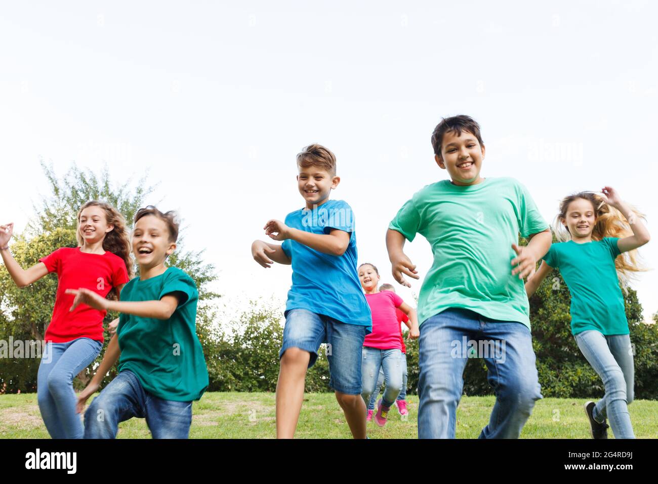 Gruppo di bambini felici che corrono all'aperto. Foto Stock