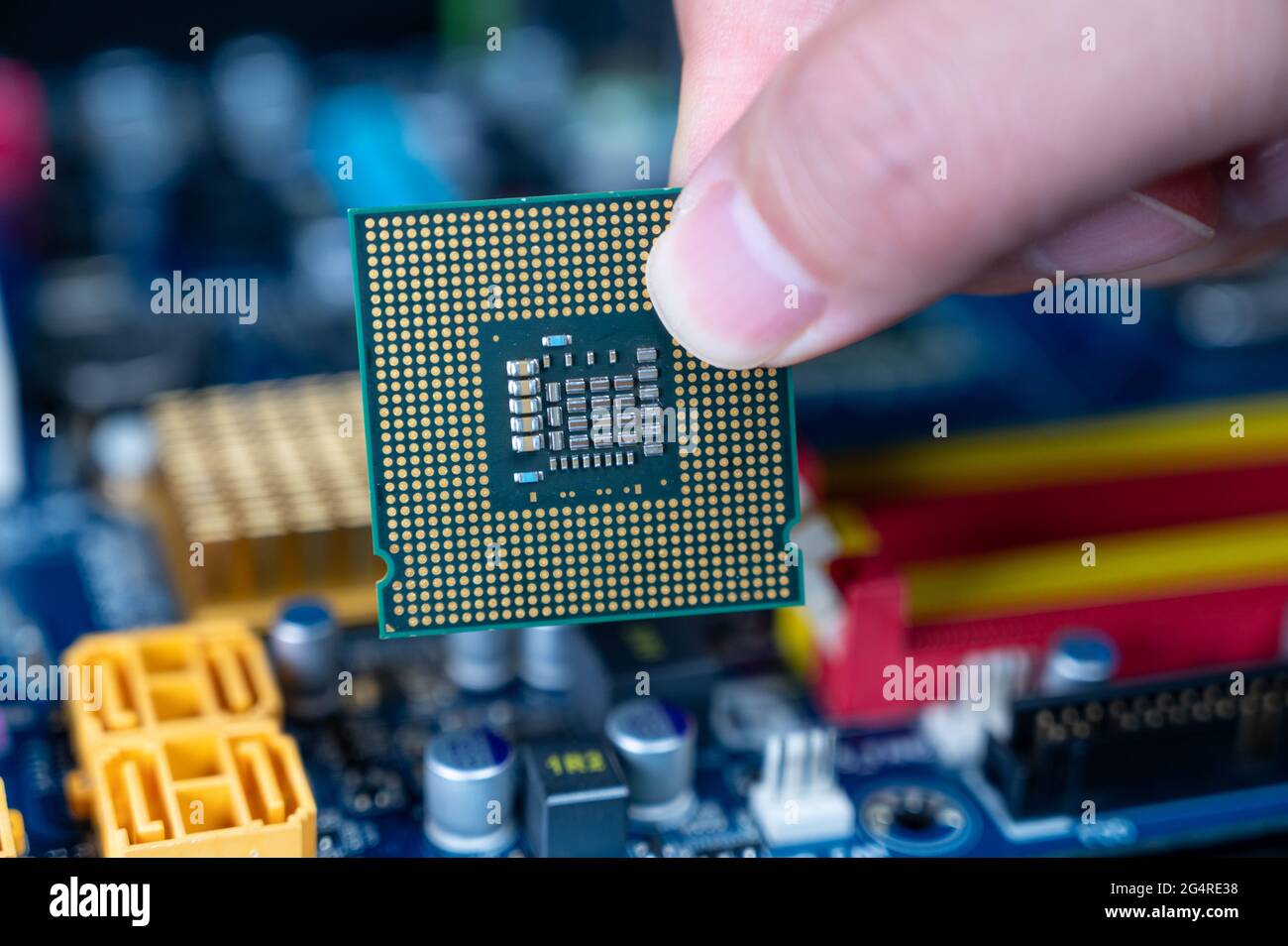 Mano con la CPU su una scheda madre del computer. Foto Stock