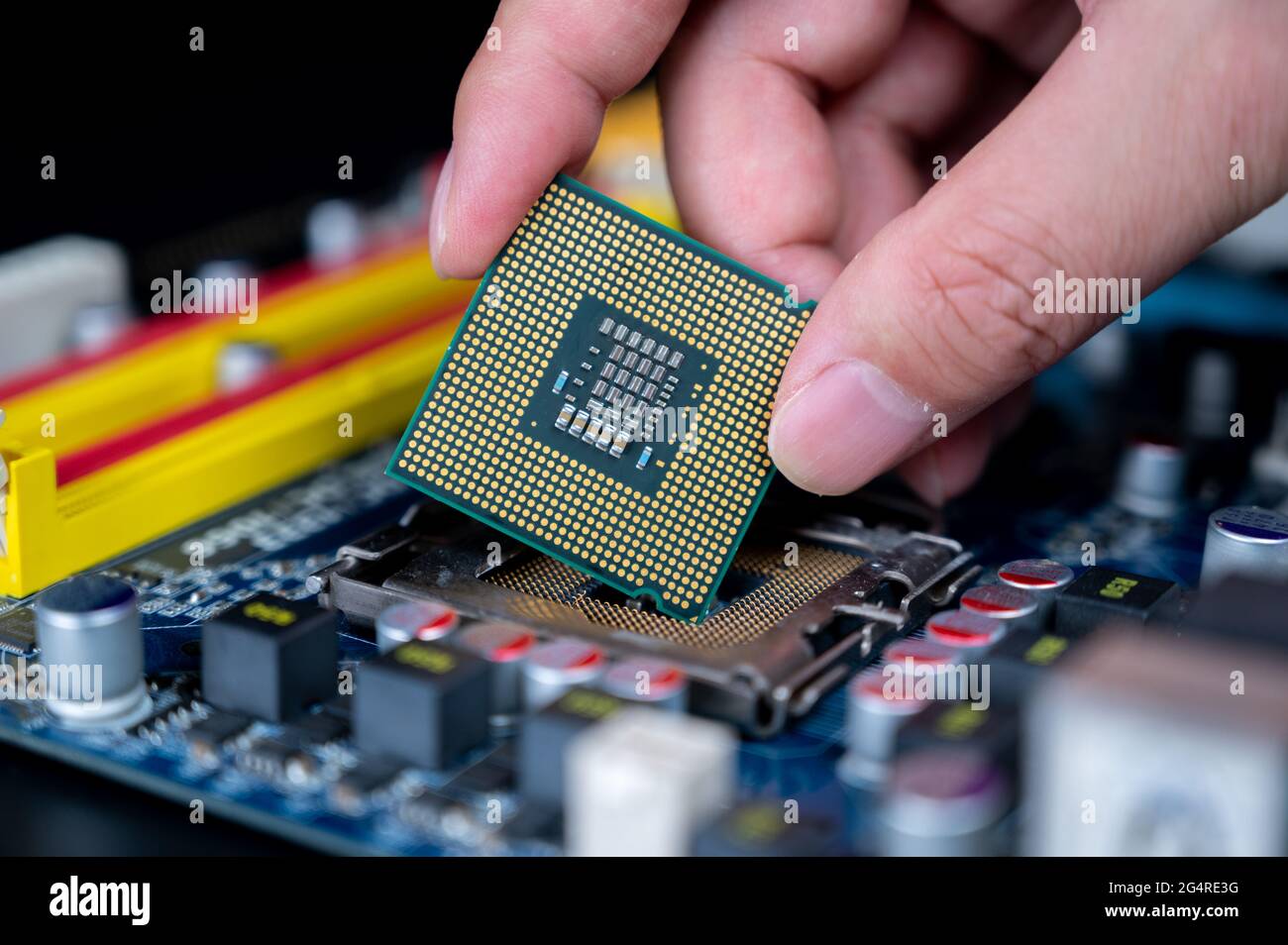 Mano con la CPU su una scheda madre del computer. Foto Stock