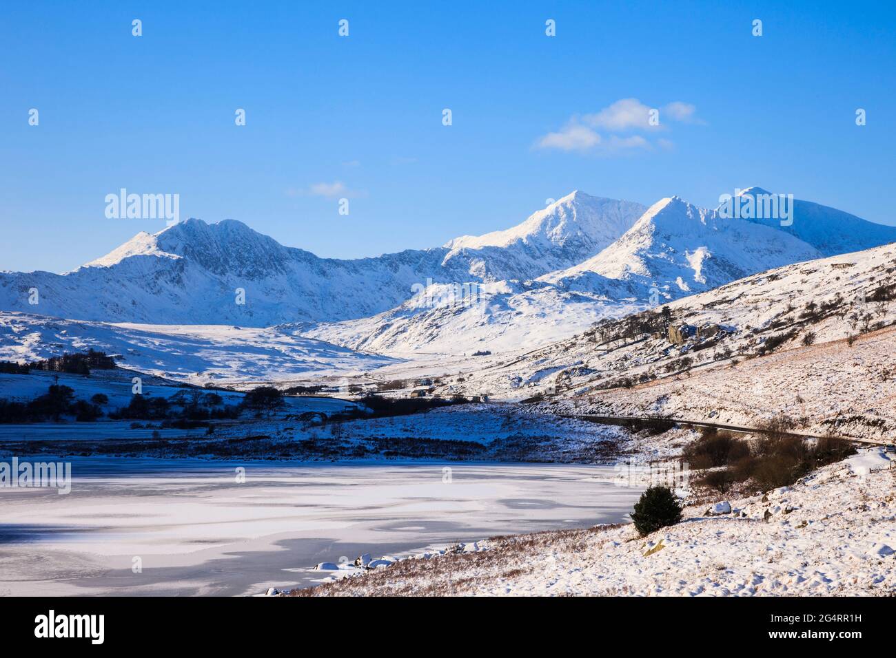 Vista attraverso i laghi ghiacciati di Llynnau Mymbyr fino al ferro di cavallo di Snowdon nel Parco Nazionale di Snowdonia con neve profonda in inverno. Capel Curig Galles del Nord Gran Bretagna Foto Stock