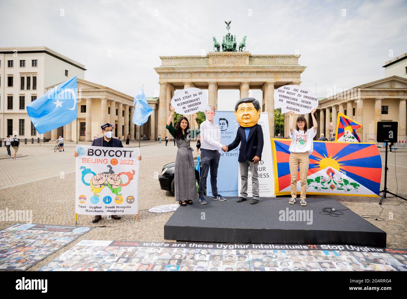 Berlino, Germania. 23 Giugno 2021. I partecipanti a una protesta di diverse organizzazioni per i diritti umani contro la consegna delle Olimpiadi invernali del 2022 a Pechino si trovano di fronte alla porta di Brandeburgo. Due partecipanti indossano maschere del presidente cinese Xi Jinping e il presidente del Comitato Olimpico Internazionale Thomas Bach stringono le mani. Credit: Christoph Soeder/dpa/Alamy Live News Foto Stock