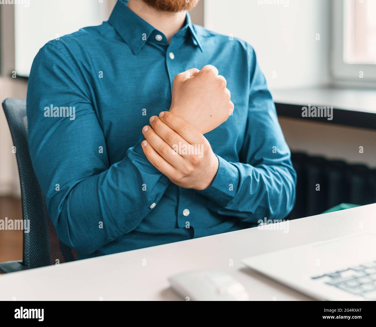 Lavoratore maschile in tuta blu che soffre di dolore al polso Foto Stock