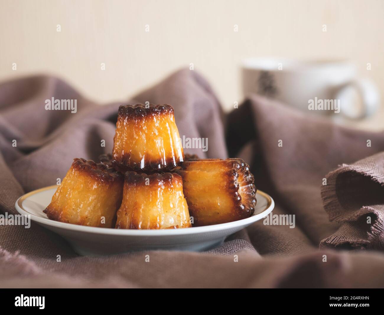 Canele con bella lucentezza su un piccolo piatto. Pasticceria francese per una colazione perfetta Foto Stock