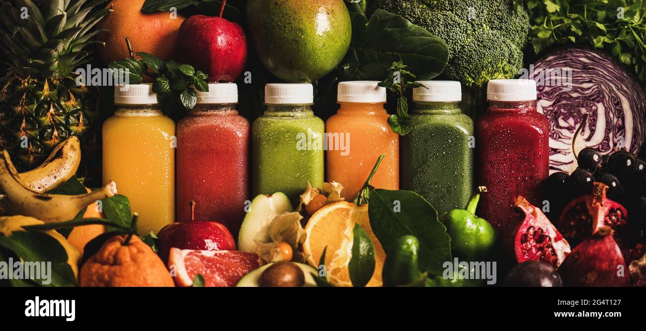 Succhi colorati in bottiglie con frutta, verdure e verdure intorno Foto Stock