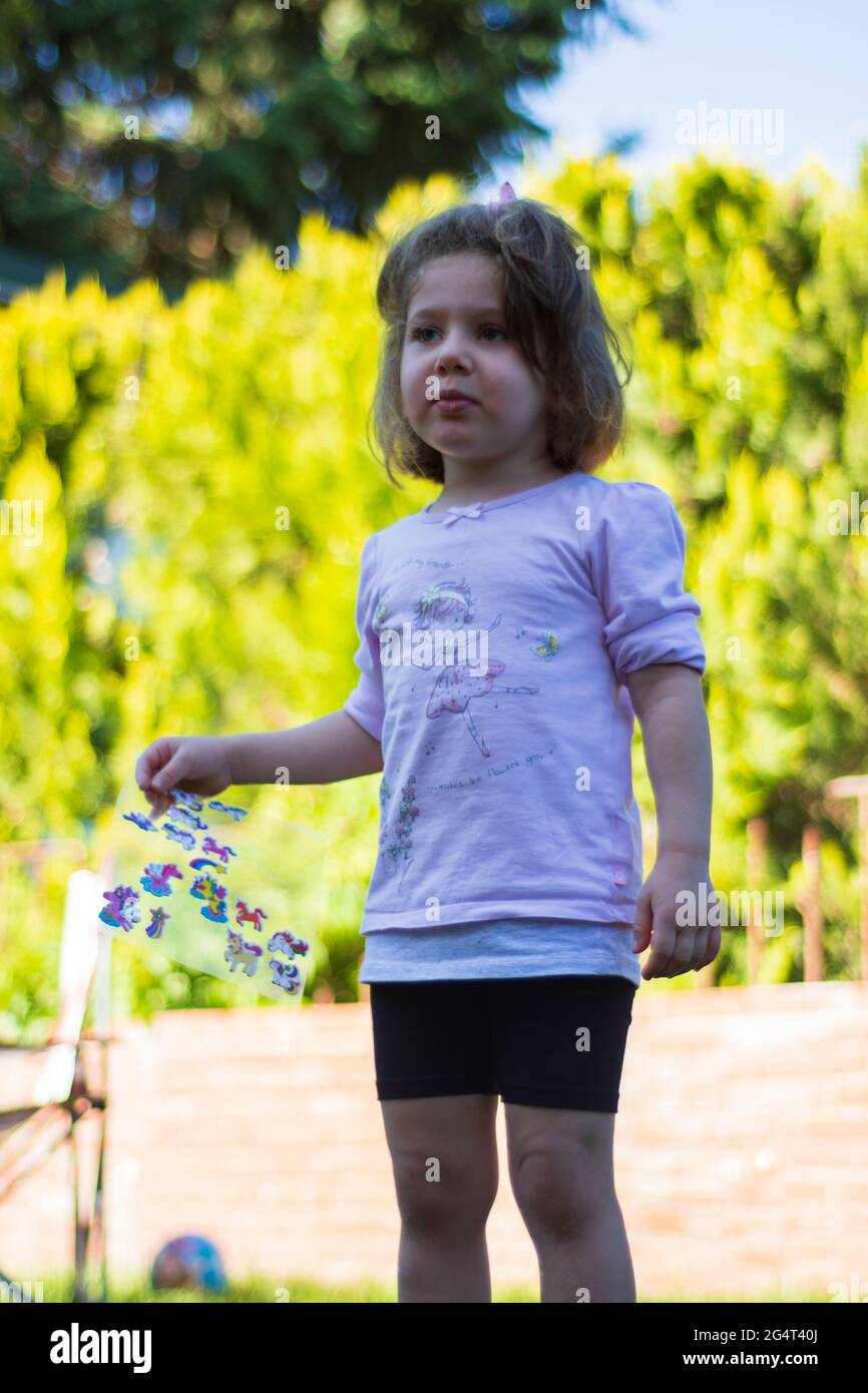 la bambina sta giocando con gli adesivi in giardino Foto Stock