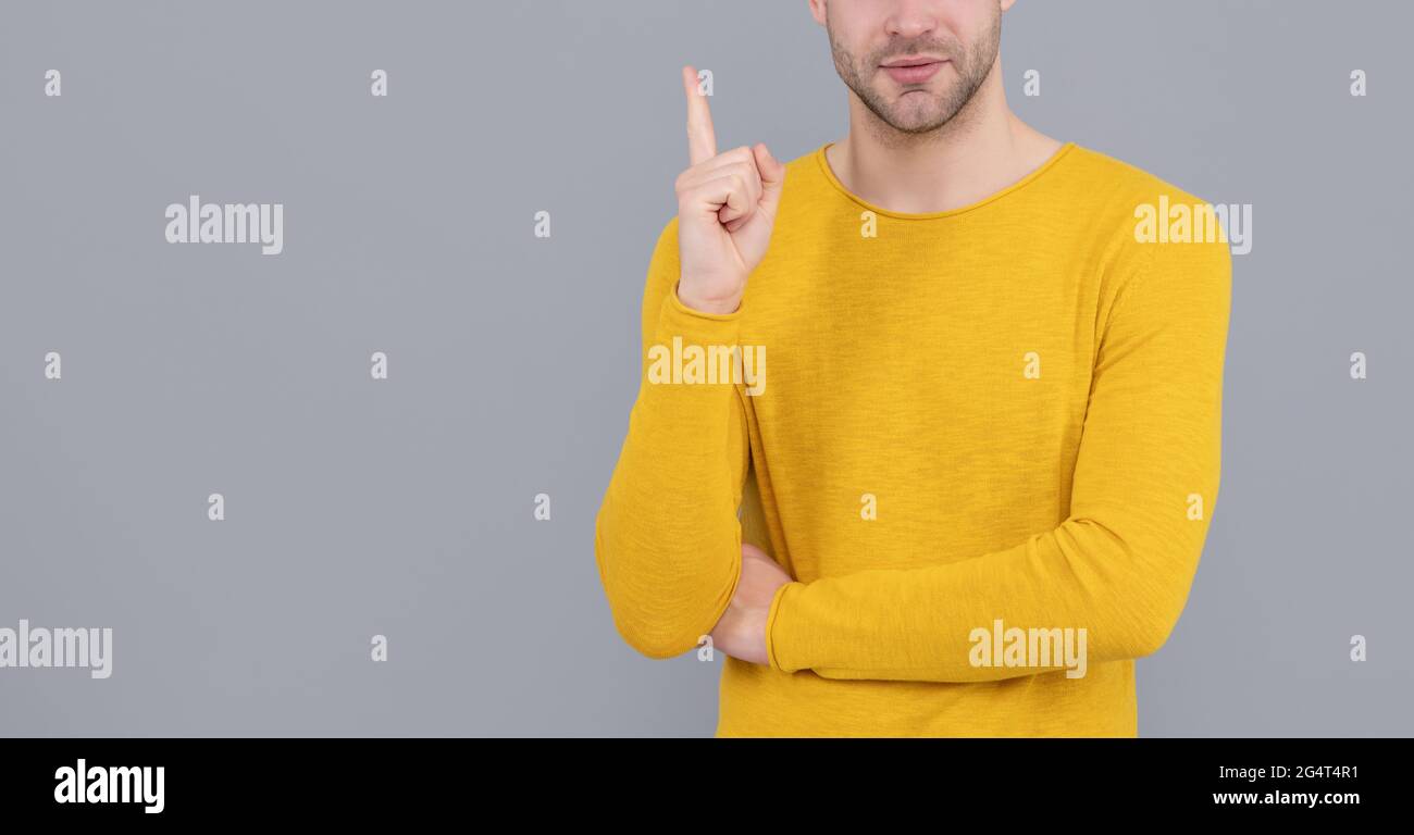Uomo non rasato in giallo maglione vista tagliata Keep Raised finger grigio sfondo spazio copia, eureka Foto Stock
