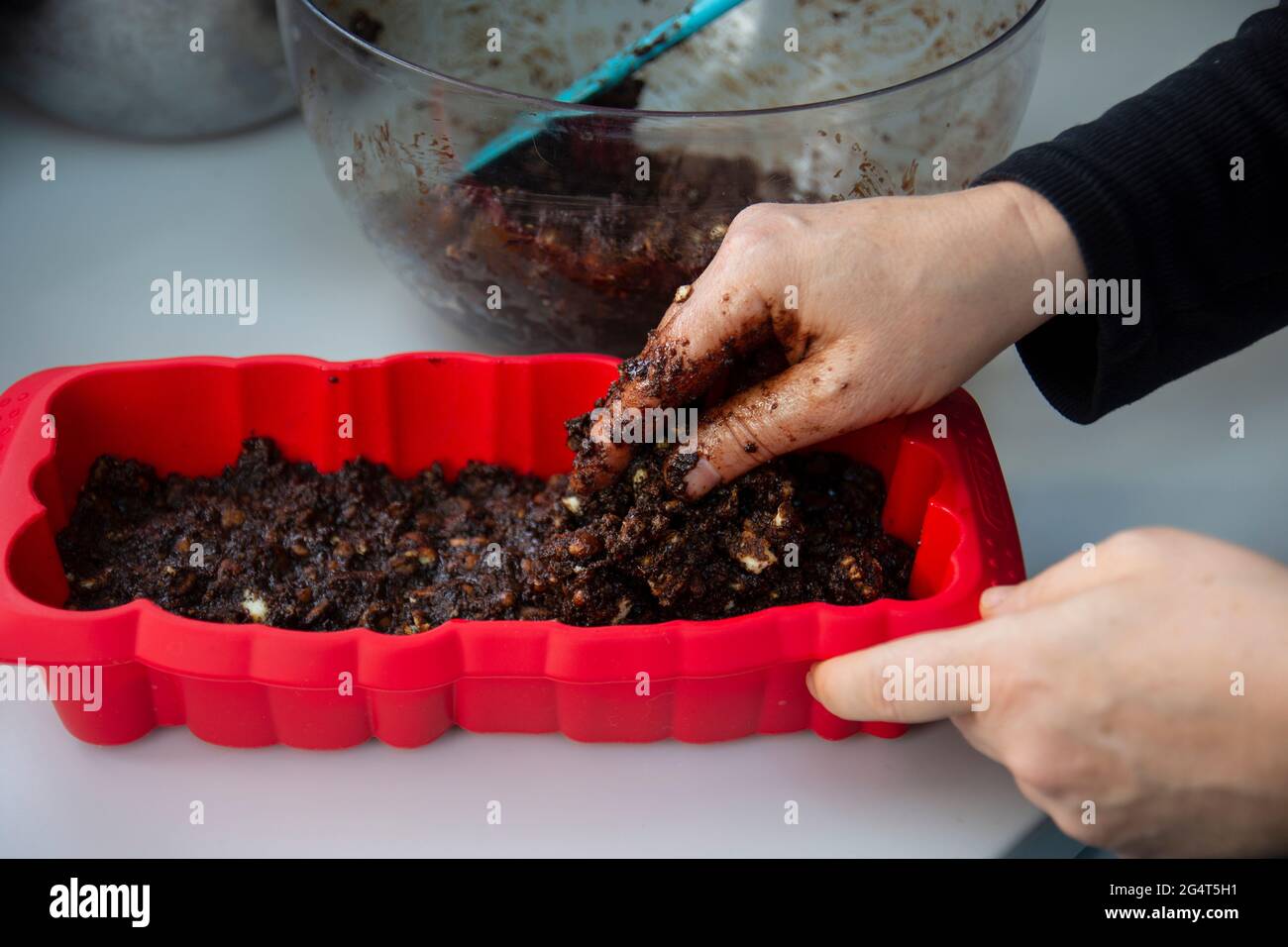 Lei sta sgretolando i biscotti. Sta facendo una torta di compleanno con biscotti e cioccolato. Torta a mosaico. Buon compleanno. Foto Stock