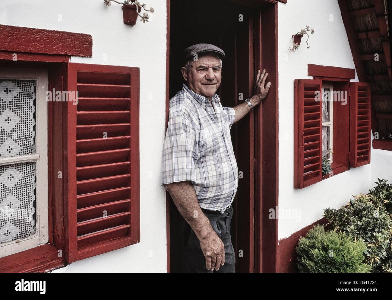 Un uomo locale alla porta della sua tradizionale casa Palheiro incorniciata A, Santana. Madeira. Portogallo Foto Stock