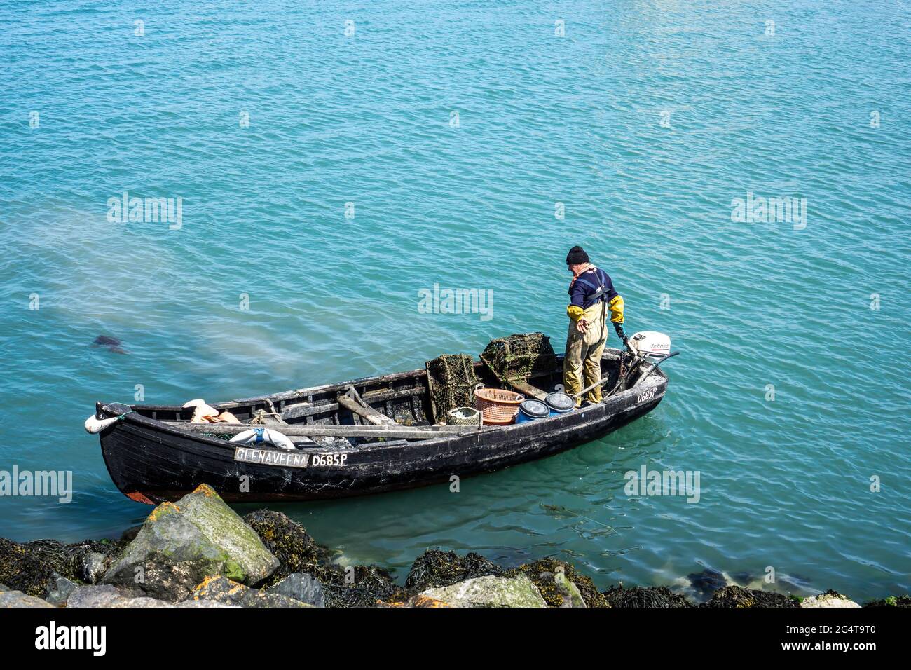 Un pescatore di aragosta al lavoro in una piccola barca nel porto di Howth a Dublino, Irlanda. Foto Stock