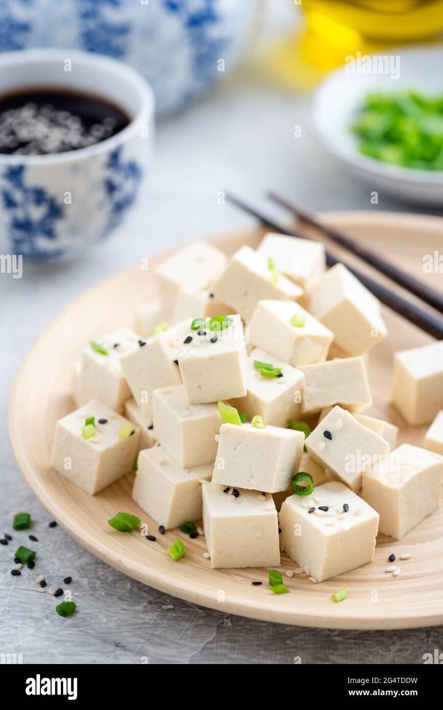 Tofu tagliato a cubetti su un piatto di bambù. Cibo asiatico Foto Stock