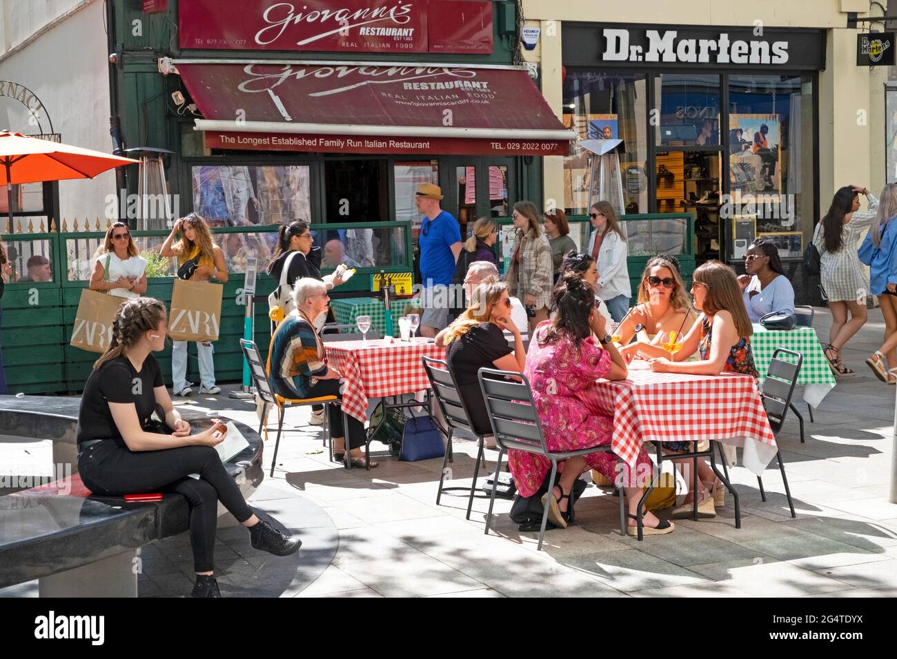 Persone socialmente distanziando seduto fuori Giovanni ristorante italiano mangiare e bere ai tavoli nel Cardiff City Centre Wales UK KATHY DEWITT Foto Stock